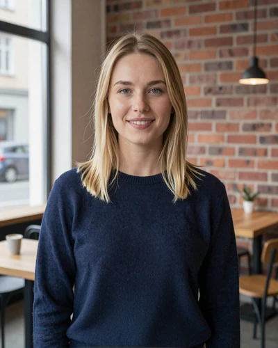Lena, 29, a blonde German woman smiling warmly in a Berlin cafe wearing a navy sweater
