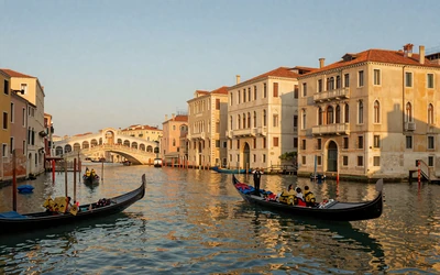 Venice Grand Canal with gondolas and Renaissance palazzos reflecting in calm water at golden hour