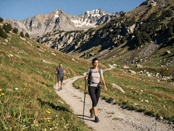Couple hiking together on a scenic Pyrenees mountain trail in Andorra with alpine meadows