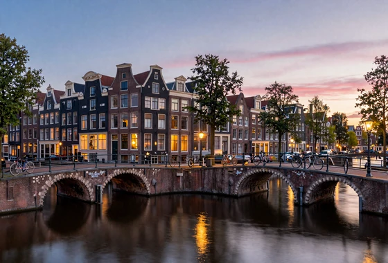 Romantic Amsterdam canal scene at dusk with traditional Dutch houses reflecting in calm water