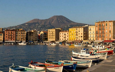 Naples waterfront with Mount Vesuvius in background and colorful buildings along the Mediterranean harbor